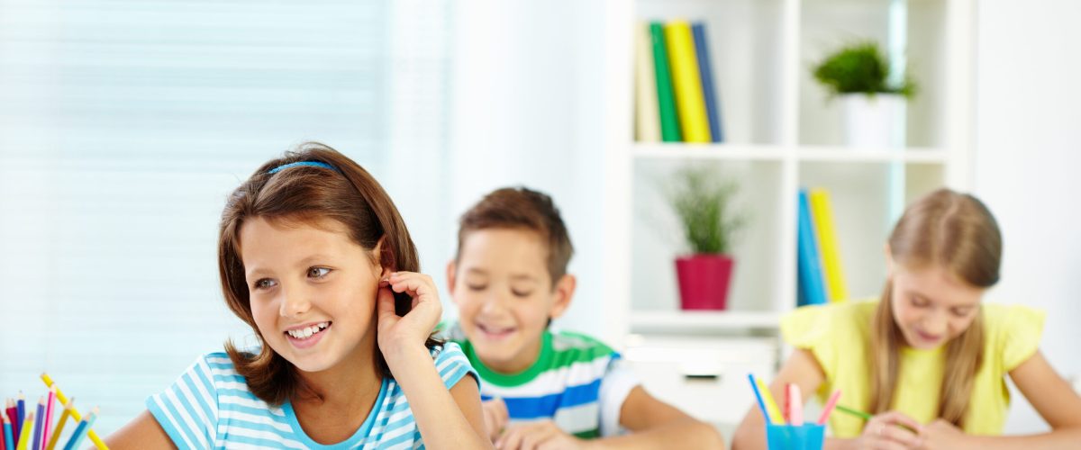 Portrait of lovely girl and her two schoolmates on background sitting at lesson